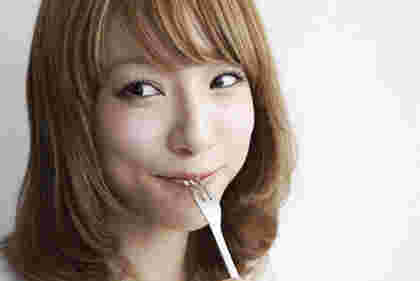 フォークで食べ物を口に運び微笑む女性