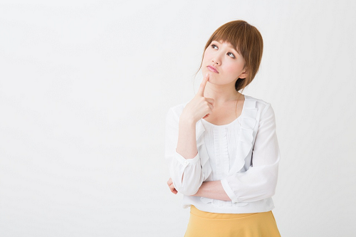 人差し指を顎に当てて考え込む女性