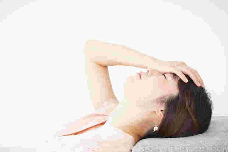 おでこに手を当て上を向いている女性