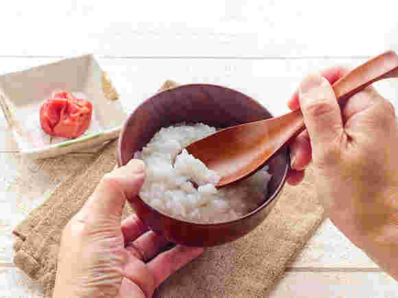 お粥をお椀によそって梅干しを添えて食べる