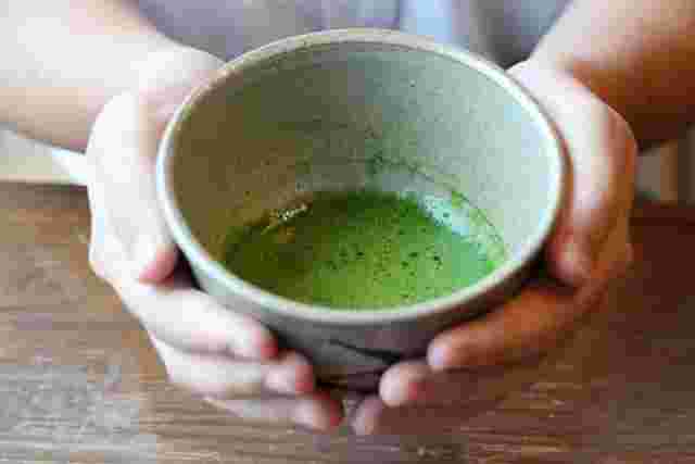 両手で抹茶が入った器を持つ画像