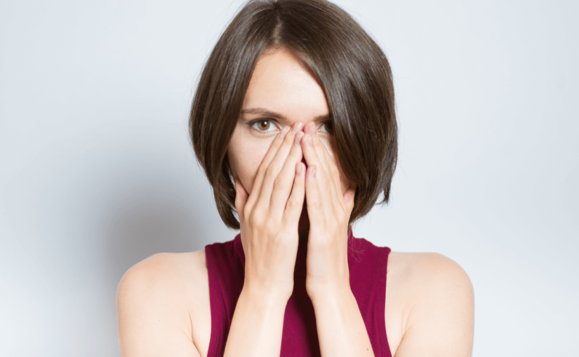 口を手でふさいでいる女性