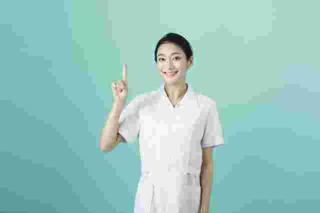 白衣を着て人差し指を立てる女性