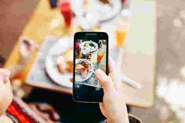 スマホで料理を撮っている女性