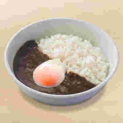真っ白な皿に入った半熟たまごの黒カレー。