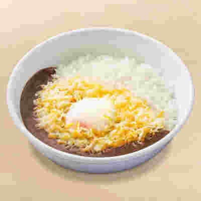 真っ白な皿に入ったチーズと半熟たまごの美味しそうな黒カレー。