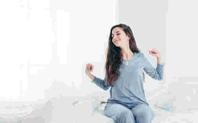 良い眠りから覚めて伸びをする女性