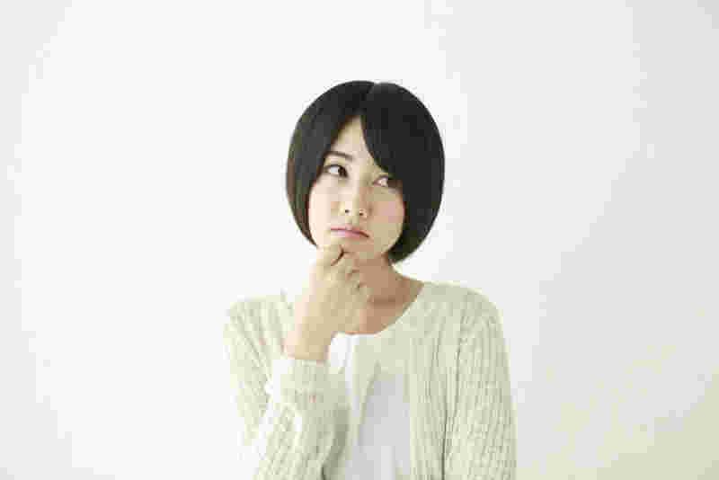 手を顎に当て考えこむ女性