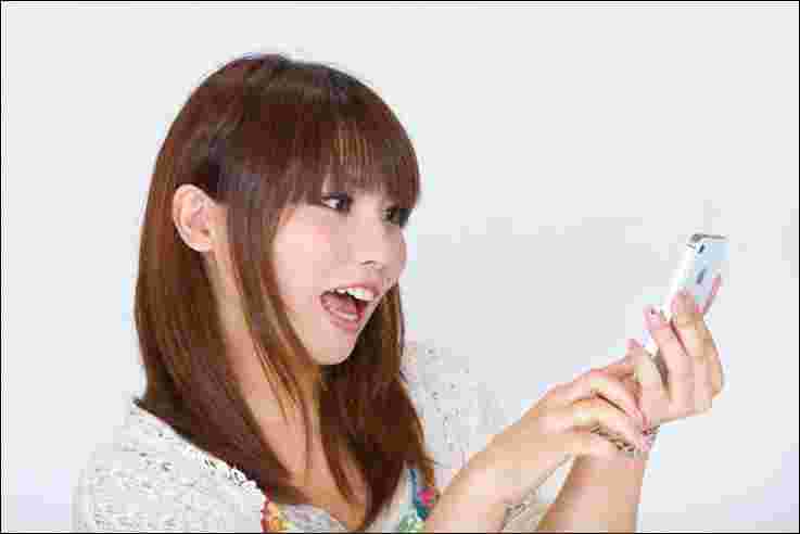 スマホを見ながら驚く女性