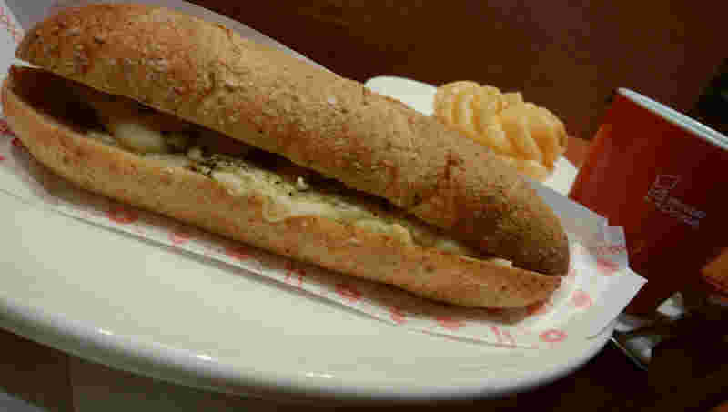 手前に大きくホットさんどとミスドのマグカップとフレンチクルーラー