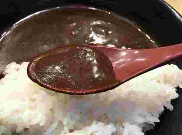 吉野家の黒カレー、ルーをスプーンですくっている