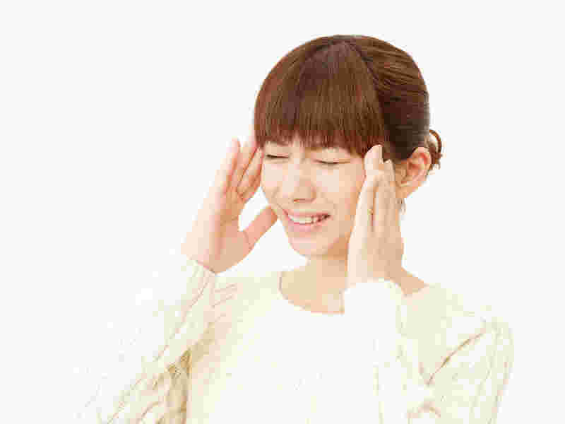 こめかみをおさえる女性