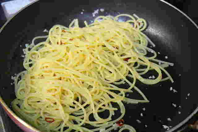 パスタとニンニクオイルを絡め合わせる様子