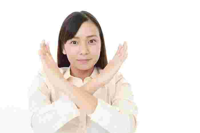 手で×マークをする女性画像