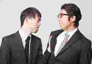 同僚の襟をつかむ男性