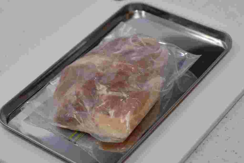 フリーザーバッグに入れ金属トレーに乗せた鶏もも肉