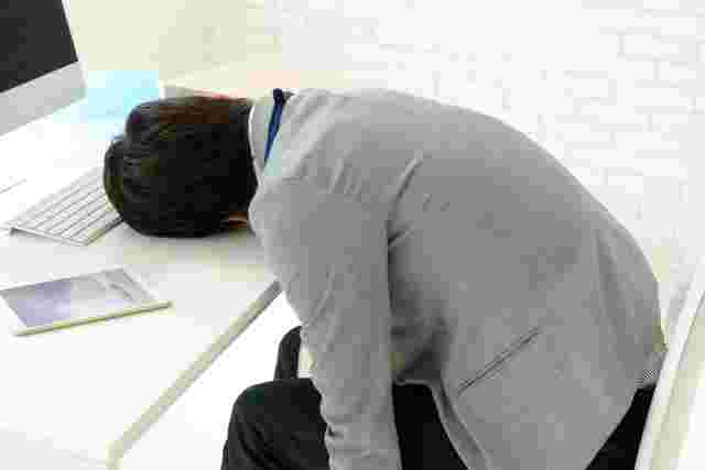 机にうなだれる男性