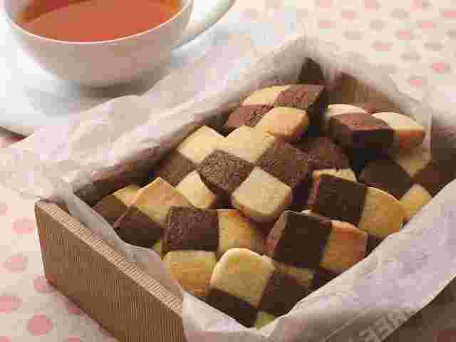 ピンクのドット柄のクロスの上に紅茶と木箱に入ったクッキー