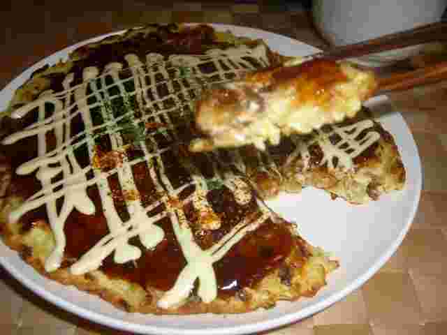 豆腐お好み焼きを一切れ箸でつまんでいる画像