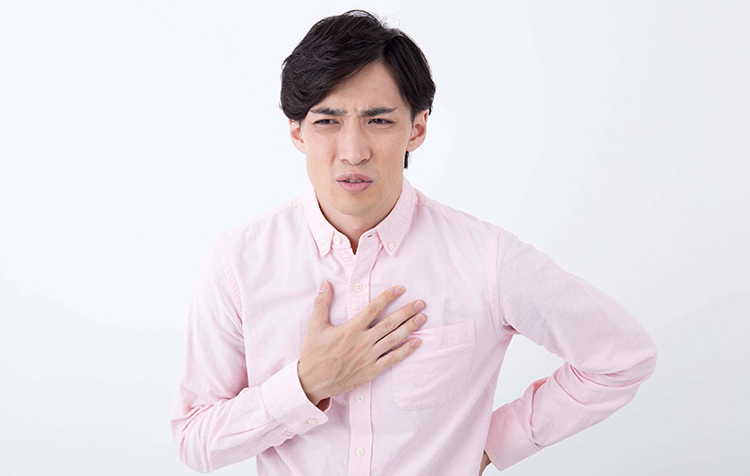 胸を押さえて気持ち悪そうに顔をしかめる男性