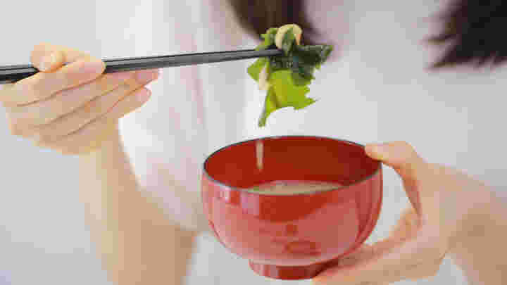 箸で味噌汁の具材を持ち上げている様子