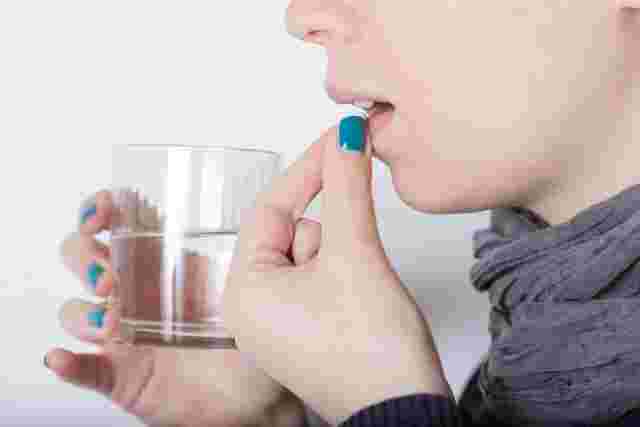 グラスを持ち錠剤を飲もうとしている女性