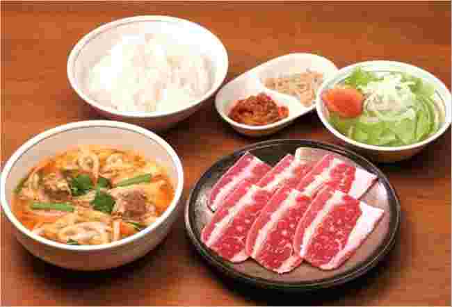 お肉とうどん、サラダ、ごはんが並んでいる様子