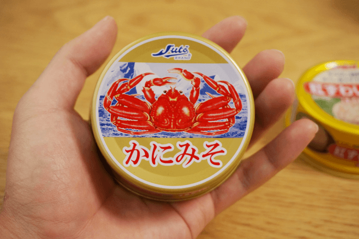 かにみその缶詰を手にのせている