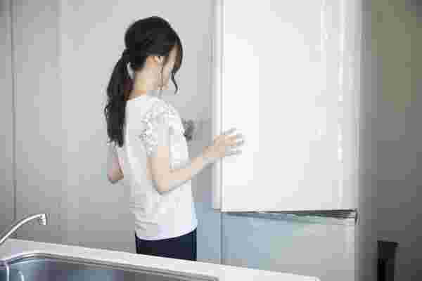 白い冷蔵庫を開ける女性