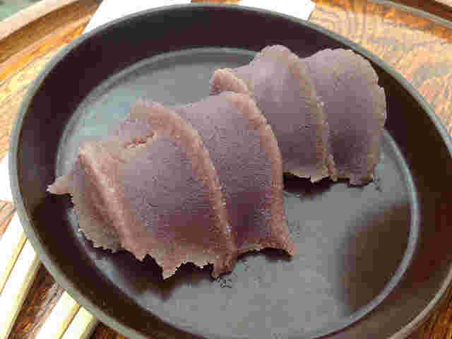 木製のお盆に黒いお皿にのった赤福