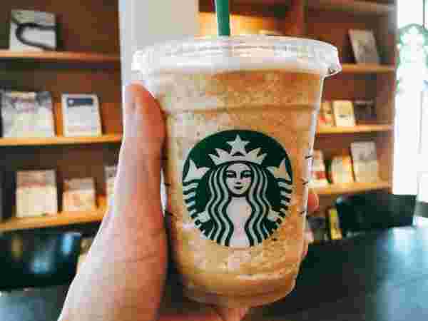 左手に持ったコーヒーフラペチーノ