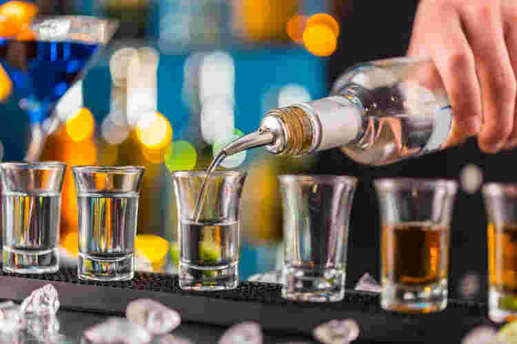 6つのショットグラスにお酒を注いでいる
