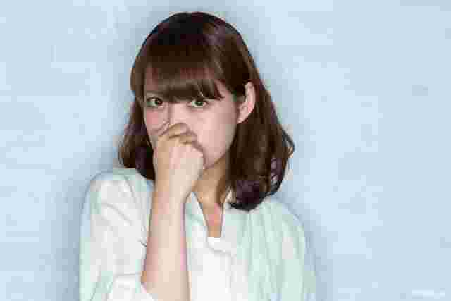 白いシャツの女性が鼻をおさえて見てる