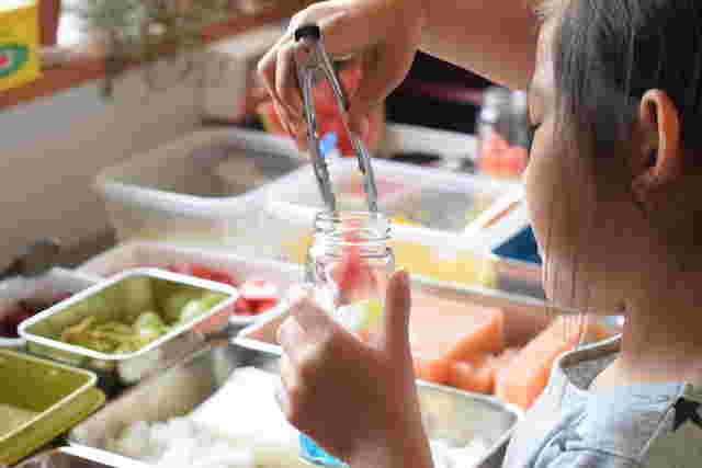何種類もある食材を前に女の子が瓶に詰める