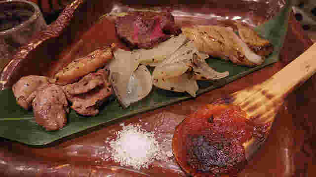 カモ、鹿、猪の肉を焼いて皿に玉ねぎと一緒に盛り付けられている