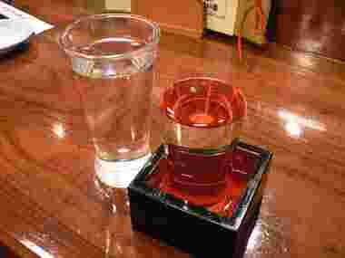 カウンターに日本酒の升と水の入ったグラスがある様子