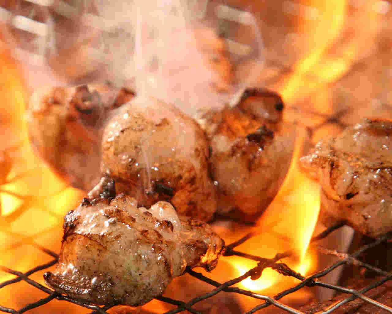 網の上で炎に包まれるおいしそうな焼き色のついたホルモン