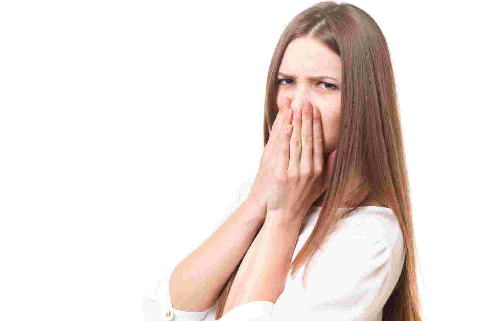 しかめっ面で両手で花を抑える女性