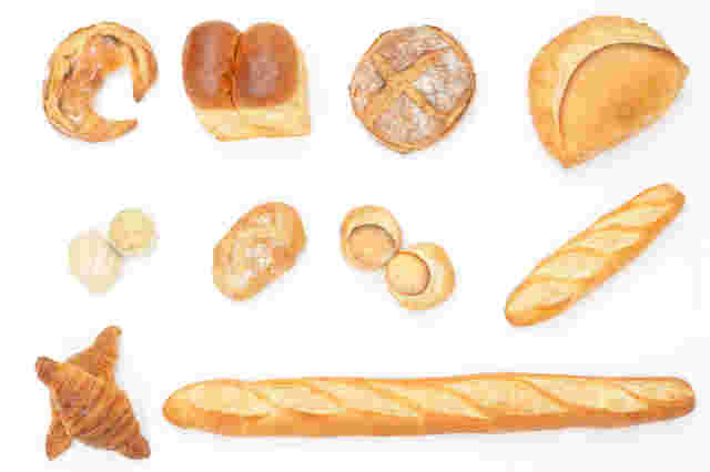 フランスパンや食パン、クロワッサンなどたくさんのパンを上から撮った画像