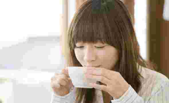 白いカップでコーヒーを飲んでいるのを楽しんでいる女性