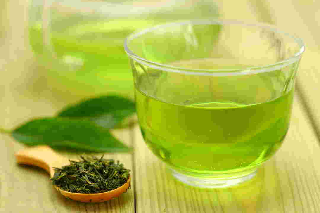 ガラスのカップに注がれた綺麗な緑色の緑茶と茶葉
