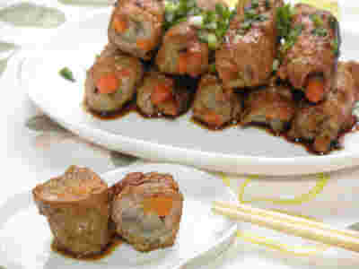 大皿にたくさん載ったごぼうと人参が巻かれた豚肉巻きと小皿にのせられた豚肉巻き