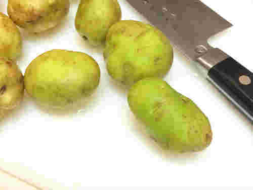 緑色に変わったじゃがいもと包丁が並んでいる様子