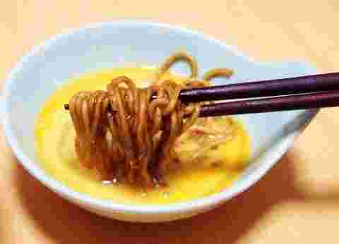 溶き卵に焼きそばをくぐらせている様子