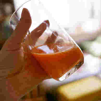 コップに入った人参ジュースを飲もうとしているところ