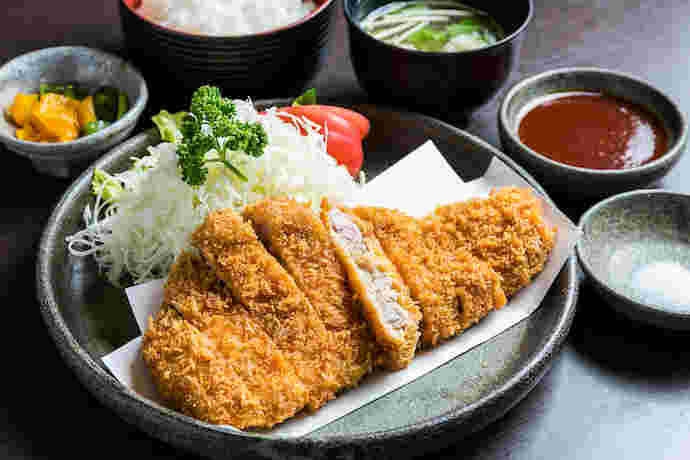 とんかつにご飯、味噌汁、キャベツ、漬物がセットになったとんかつ定食の様子