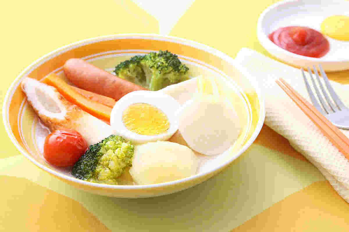 黄色い柄入りのクロスの上に黄色い柄の入った器にかぶの洋風おでん