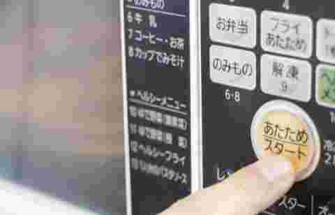 電子レンジのスタートボタンを押している指