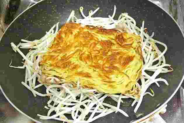 もやしの上に麺を乗せて焼きそばを作る様子