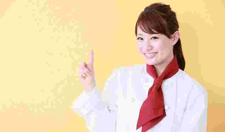 笑顔で指さしする女性料理人